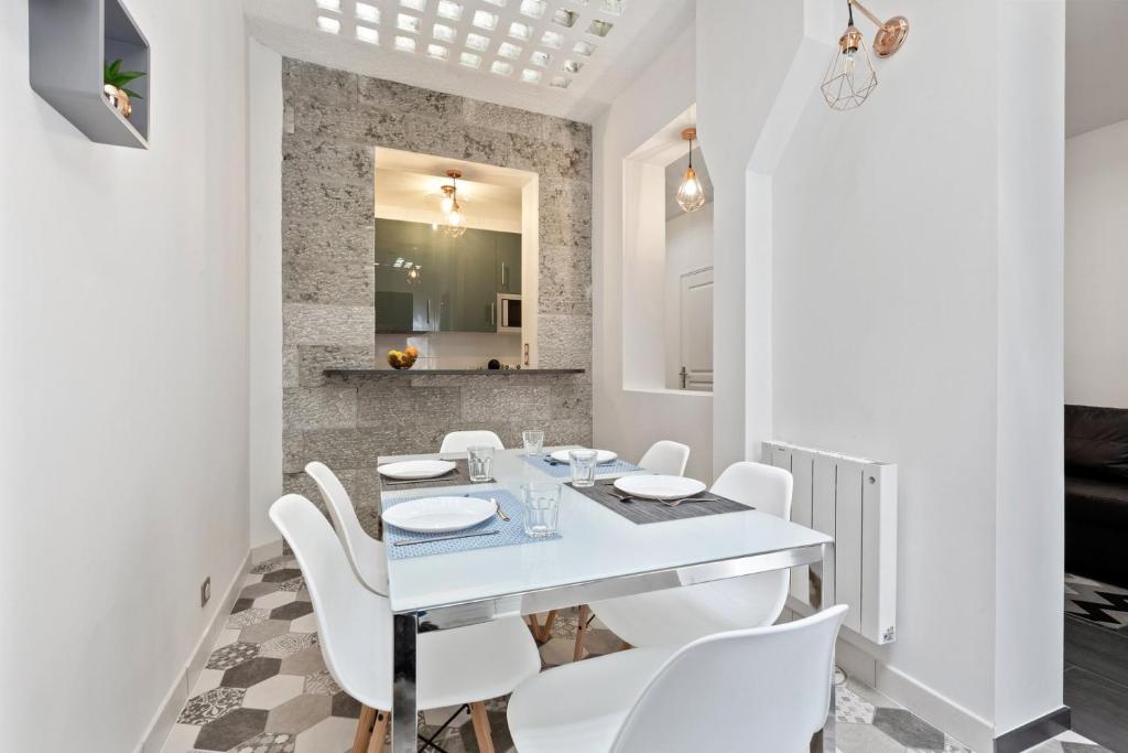 une salle à manger blanche avec une table blanche et des chaises blanches dans l'établissement GuestReady - Nice apartment for 6 in Paris, à Paris