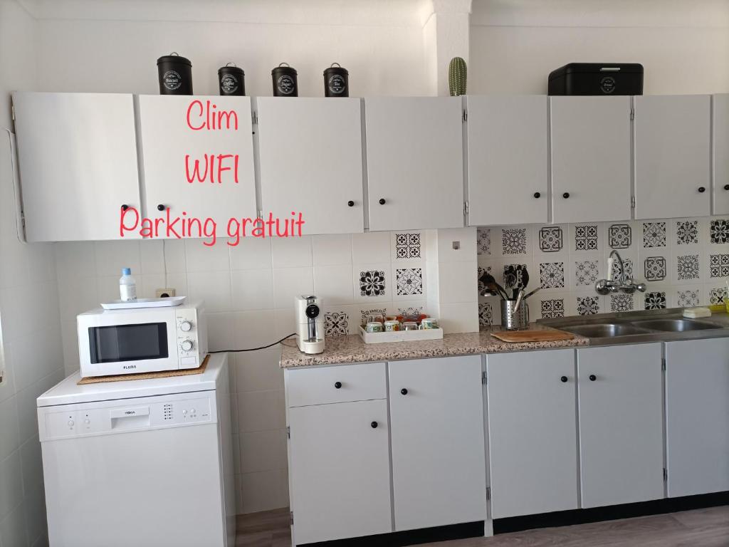 uma cozinha com armários brancos e um micro-ondas em AU COEUR D'OLHAO em Olhão