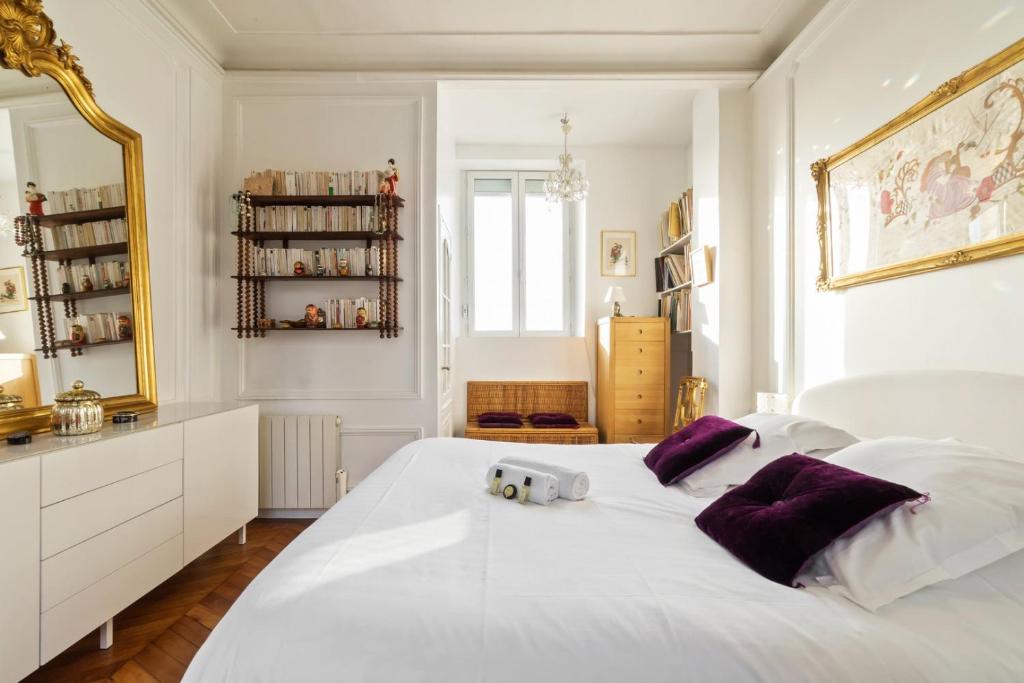 a bedroom with a large white bed with purple pillows at GuestReady - Stylish Vintage 3BR Apartment in Le Marais in Paris