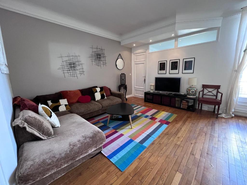 uma sala de estar com um sofá e uma televisão em GuestReady - Amazing 2BR Flat near Passy Village em Paris