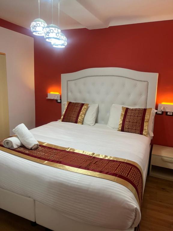 a bedroom with a large white bed with red walls at Hotel Veronese in Genoa