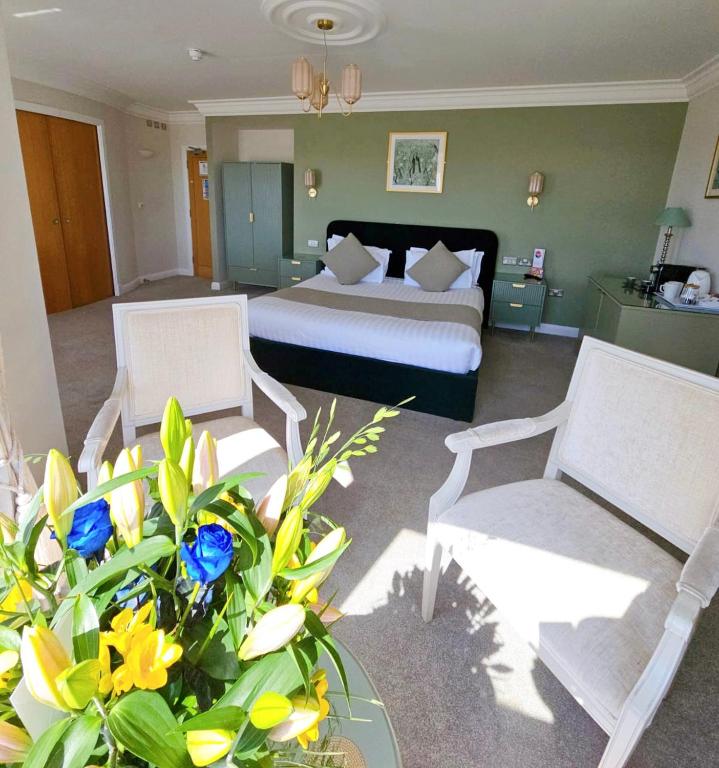 a hotel room with a bed and two chairs and flowers at Legends Hotel in Brighton & Hove