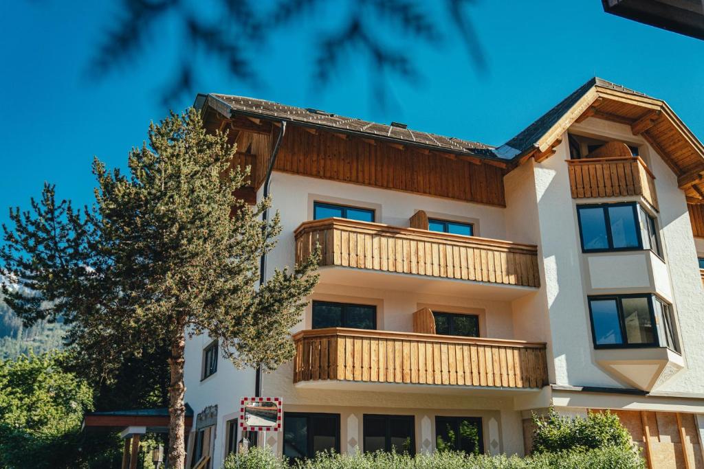 an apartment building with a balcony and a tree at Stadtvilla Schladming Boutiquehotel in Schladming