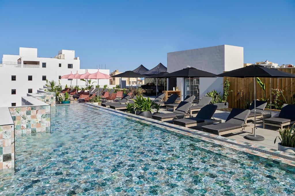 basen z leżakami i parasolami w budynku w obiekcie Stic Urban Hotel & SPA w mieście San Antonio