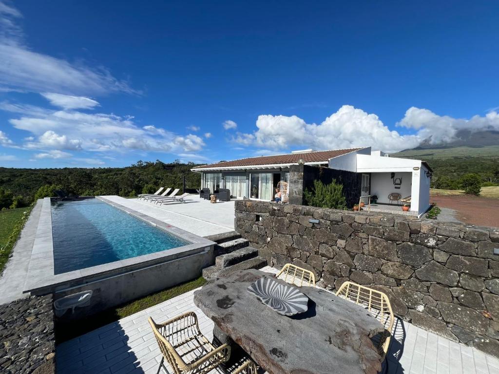 a house with a swimming pool and a stone wall at PicoTerrace in Madalena