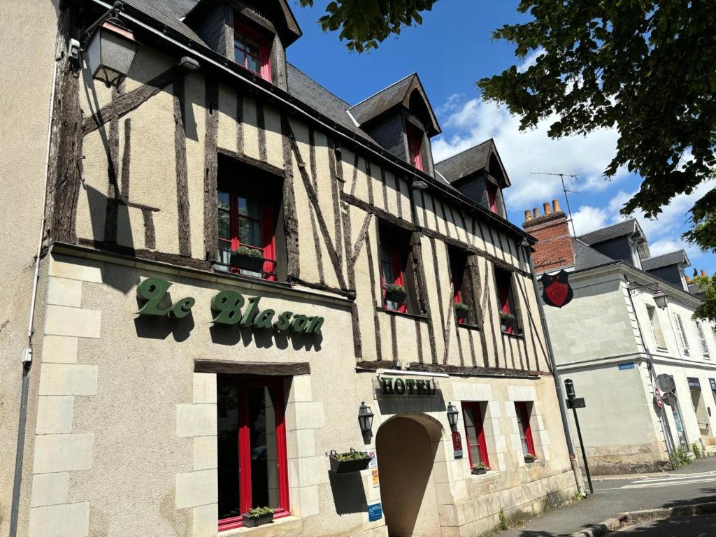 un edificio con puertas rojas y ventanas en una calle en Hôtel Le Blason, en Amboise