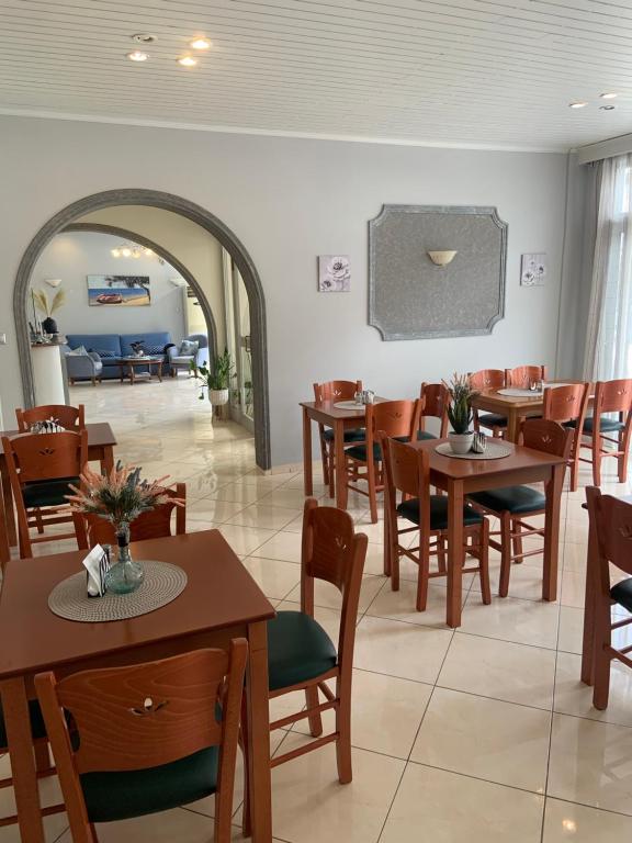 a restaurant with tables and chairs and a living room at Isidora Hotel in Agia Marina Aegina