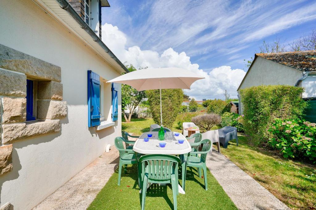 une table et des chaises avec un parasol sur l'herbe dans l'établissement Jolie maison familiale et colorée pour 6, au Guilvinec