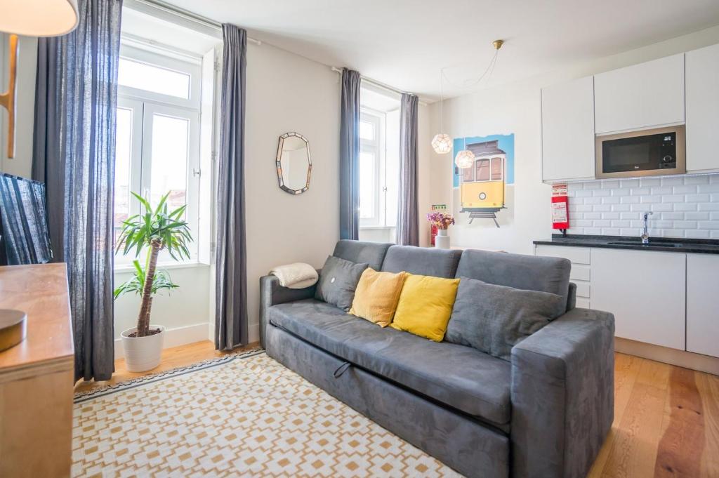 ein Wohnzimmer mit einem grauen Sofa und einer Küche in der Unterkunft GuestReady - Chic and vibrant stay near Anjos in Lissabon