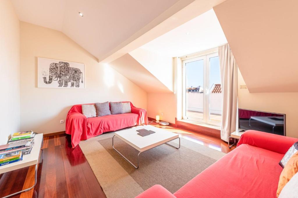- un salon avec un canapé rouge et une table dans l'établissement GuestReady - Rare Terrace Apt, Historic Center, à Lisbonne