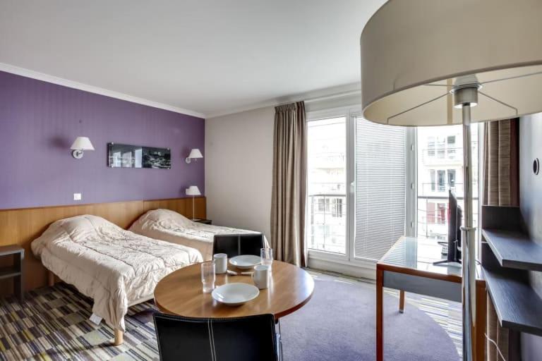 a hotel room with a bed and a table and a bedroom at GuestReady - Studio near Porte de Versailles Metro in Issy-les-Moulineaux