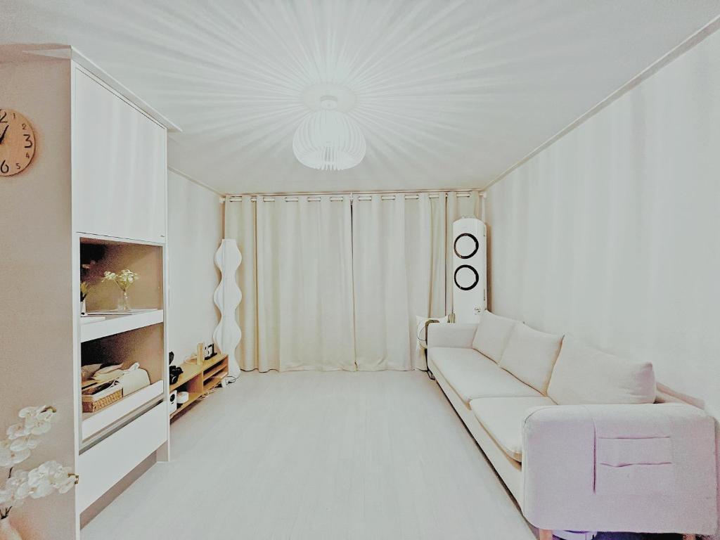 ソウルにあるSeoul Namsan Stayの白いリビングルーム(ソファ、時計付)