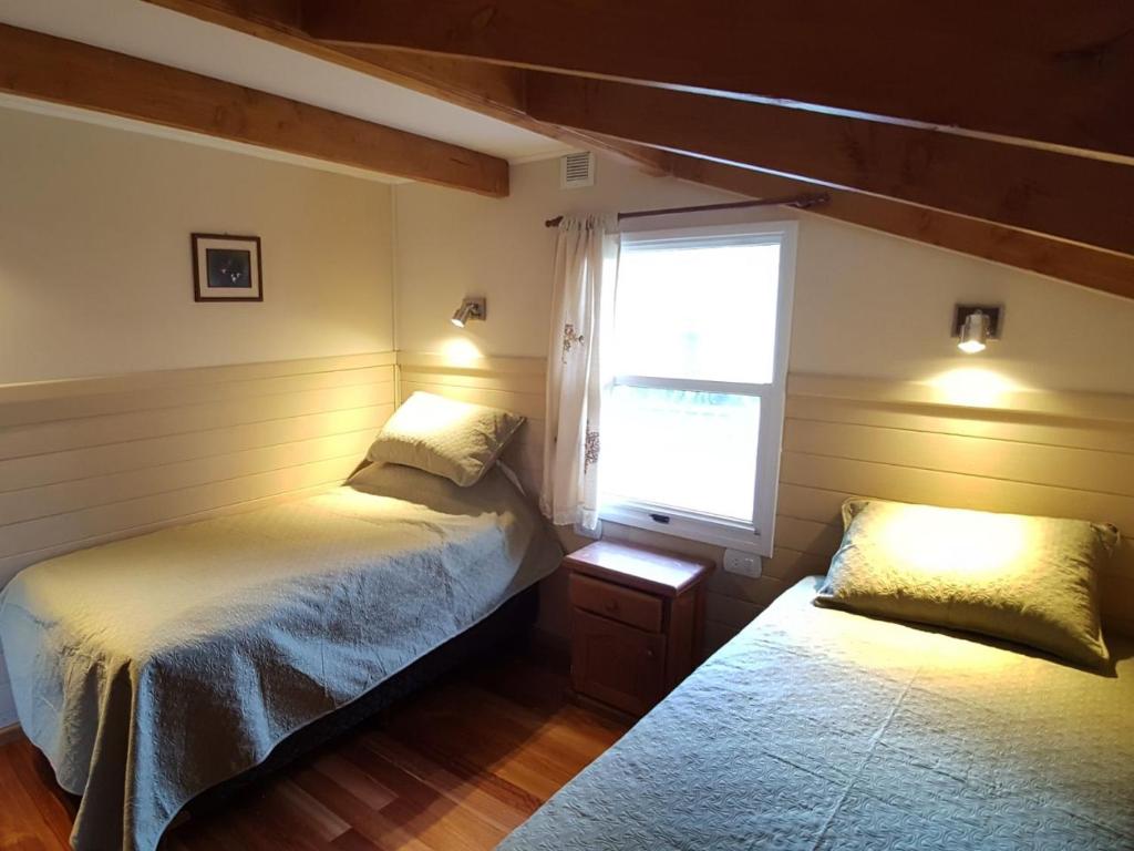 Un dormitorio con dos camas y una ventana. en Cabañas Terra, en Lago Puelo