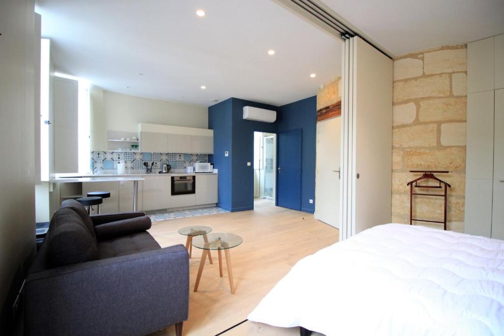 1 dormitorio con paredes azules, sofá y cocina en GuestReady - Charming apartment in Place de la Comédie, en Burdeos