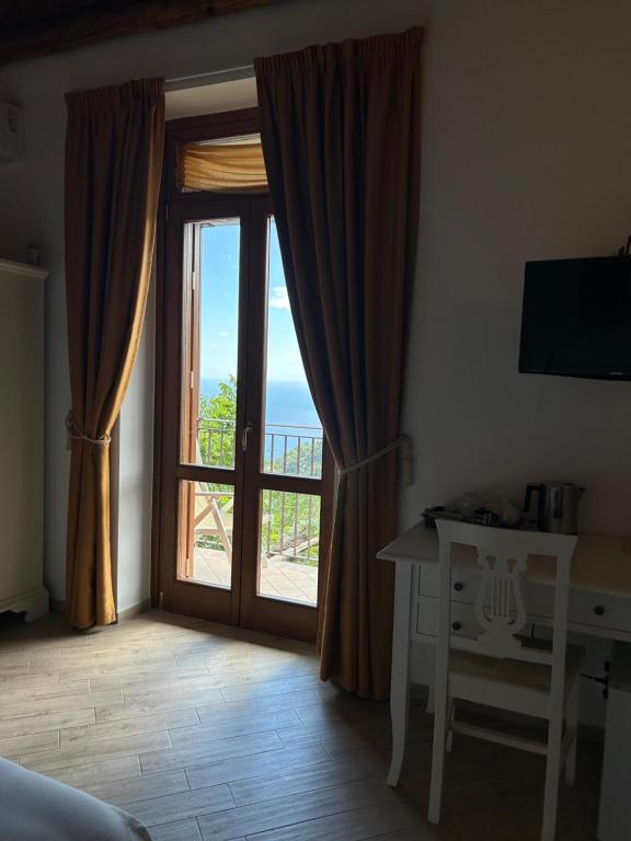 a bedroom with a sliding glass door with a view of the ocean at Agriturismo Orrido di Pino in Agerola