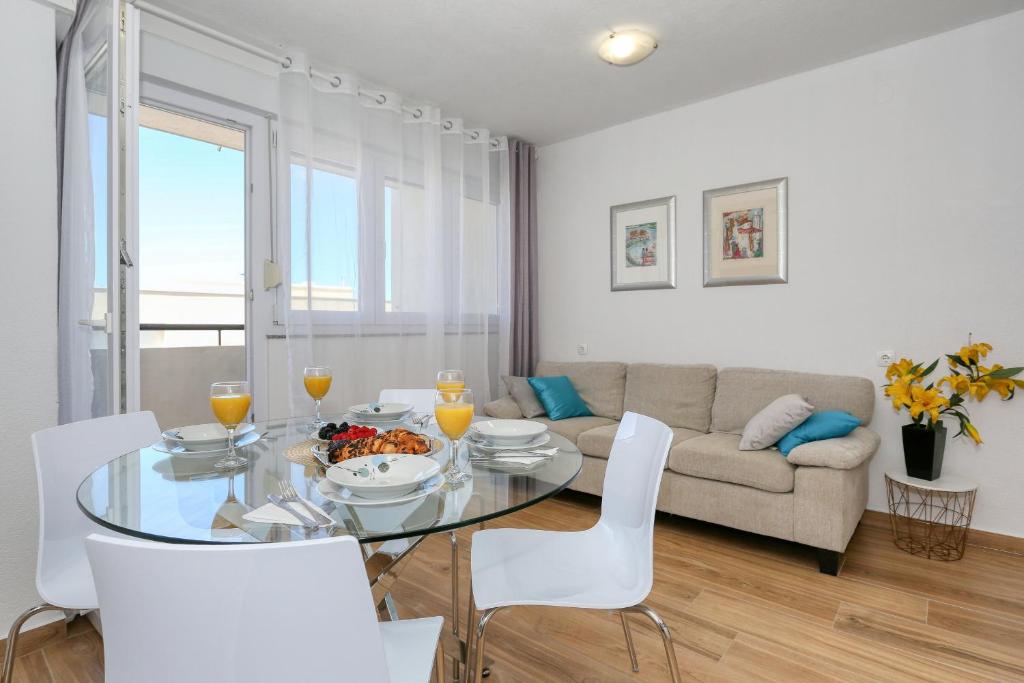 a living room with a glass table and white chairs at Apartment Ivica in Zadar