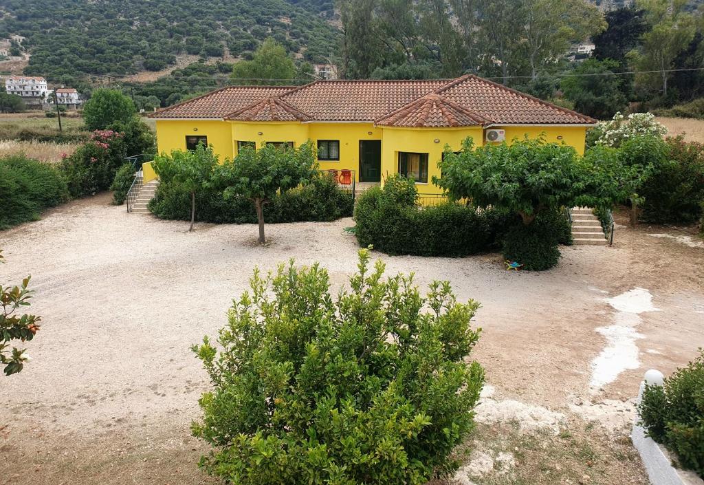 una casa amarilla con muchos arbustos y árboles en Countryside Studios en Ayia Evfimia