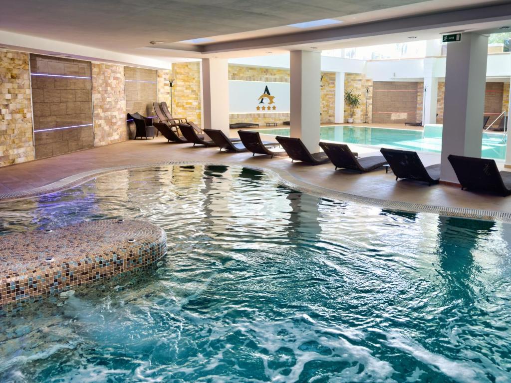 una piscina con sillas en un hotel en Hotel Atlantis Wellness & Conference, en Hajdúszoboszló