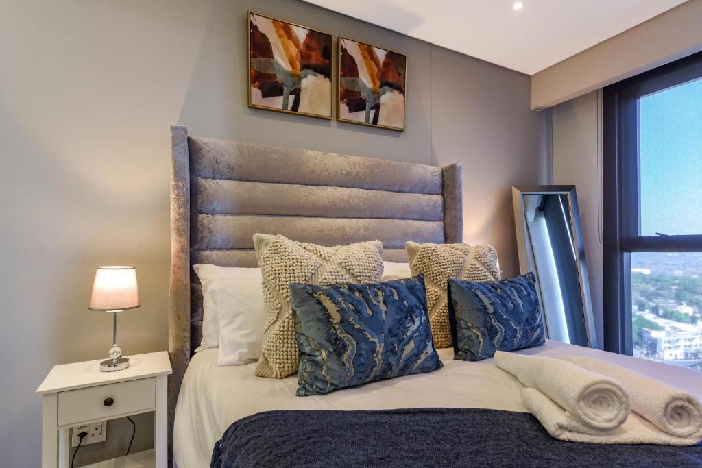 1 dormitorio con cama con almohadas y ventana en Park Central Residence - Building with Generator, en Johannesburgo