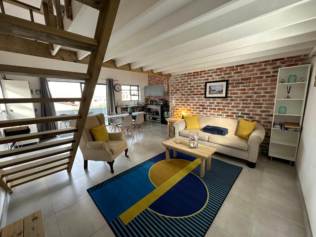 uma sala de estar com uma parede de tijolos em Modern apartments downtown em Plettenberg Bay