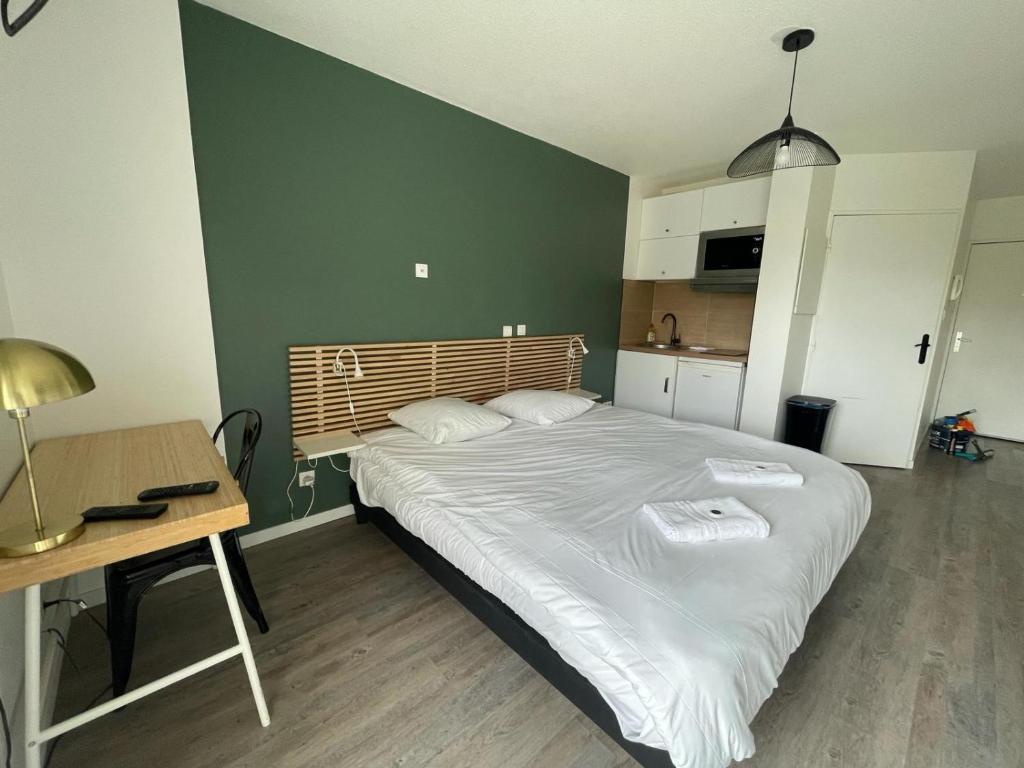 1 dormitorio con cama, mesa y escritorio en Bel appartement design tout confort (Parking Gratuit) à 10 minutes de Bordeaux, en Cenon