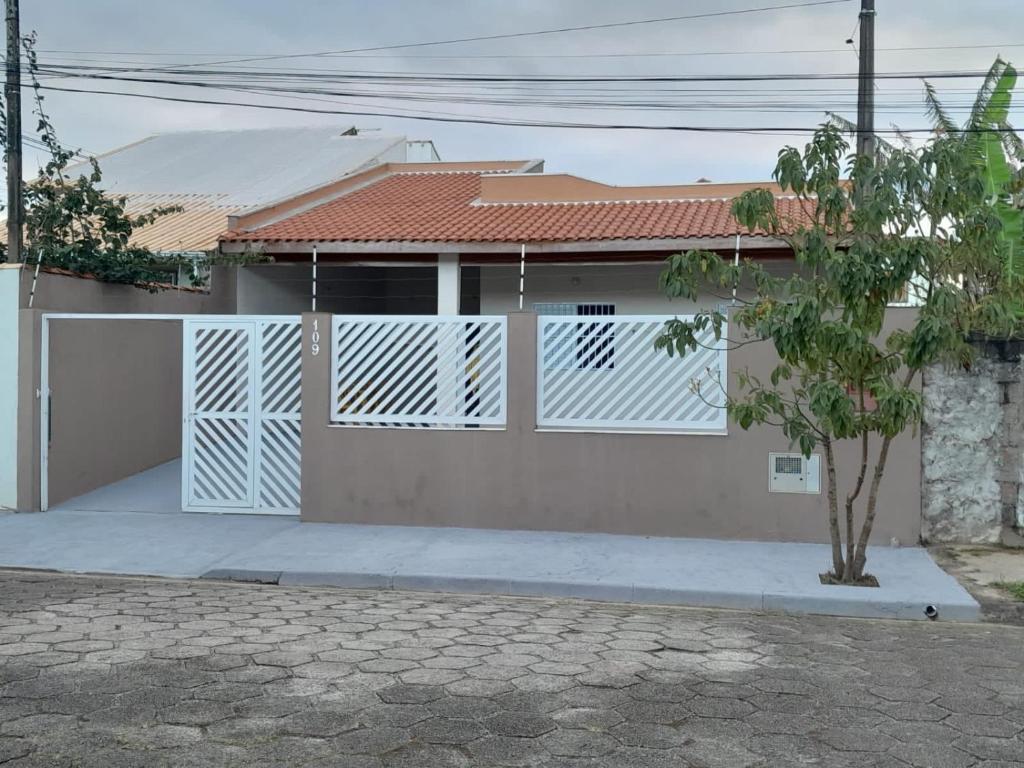 une maison avec une porte blanche et un arbre dans l'établissement Casa Peruíbe - Ótima localização, à Peruíbe