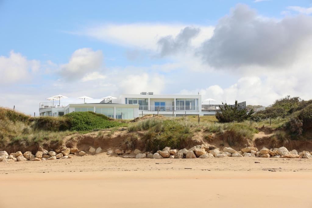 a house on top of a hill next to a beach at Hôtel & Spa Le Grand Large in Dolus d'Oléron