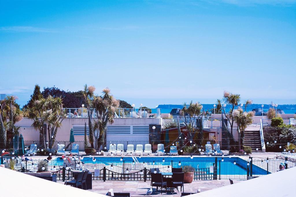 a pool with tables and chairs next to a building at TLH Derwent Hotel - TLH Leisure, Entertainment and Spa Resort in Torquay