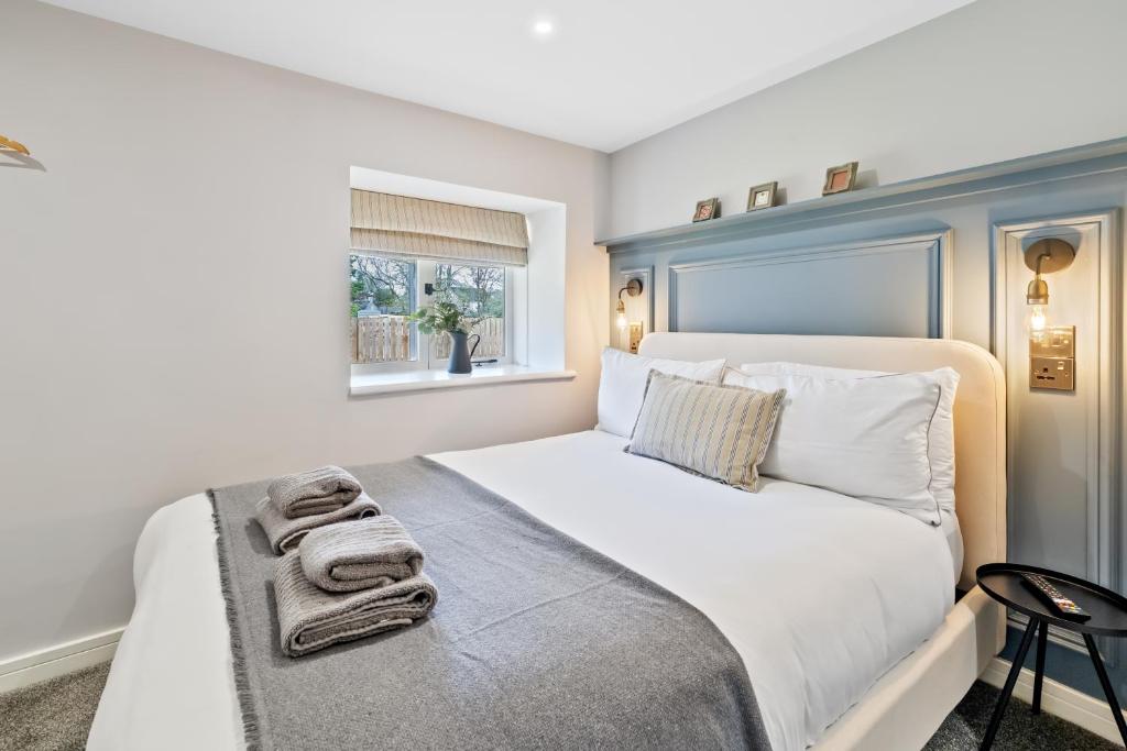 a bedroom with a white bed with a window at CORN FLOUR LODGE at PITKERRO MILL, 3 double bedrooms with TVs, 1 en-suite, 2 further bathrooms, fully equipped kitchen, large family dining area, FREE parking and WiFi, HOT TUB, private garden, short mid and longterm stays available with HONEYCOMB HOSTS in Dundee