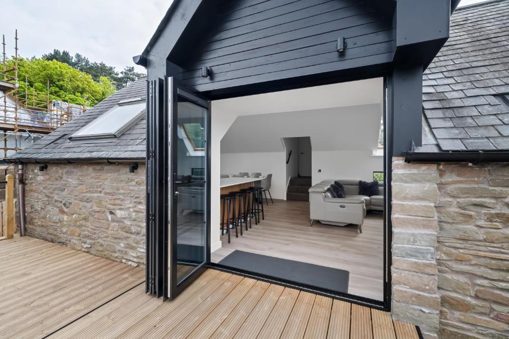 Una ampliación de una casa con puertas corredizas de vidrio. en CORN FLOUR LODGE at PITKERRO MILL, 3 double bedrooms with TVs, 1 en-suite, 2 further bathrooms, fully equipped kitchen, large family dining area, FREE parking and WiFi, HOT TUB, private garden, short mid and longterm stays available with HONEYCOMB HOSTS, en Dundee