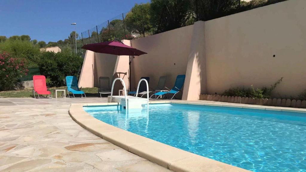 - une piscine avec des chaises et un parasol à côté d'un bâtiment dans l'établissement La Maison de Fransou, à La Roquette-sur-Siagne
