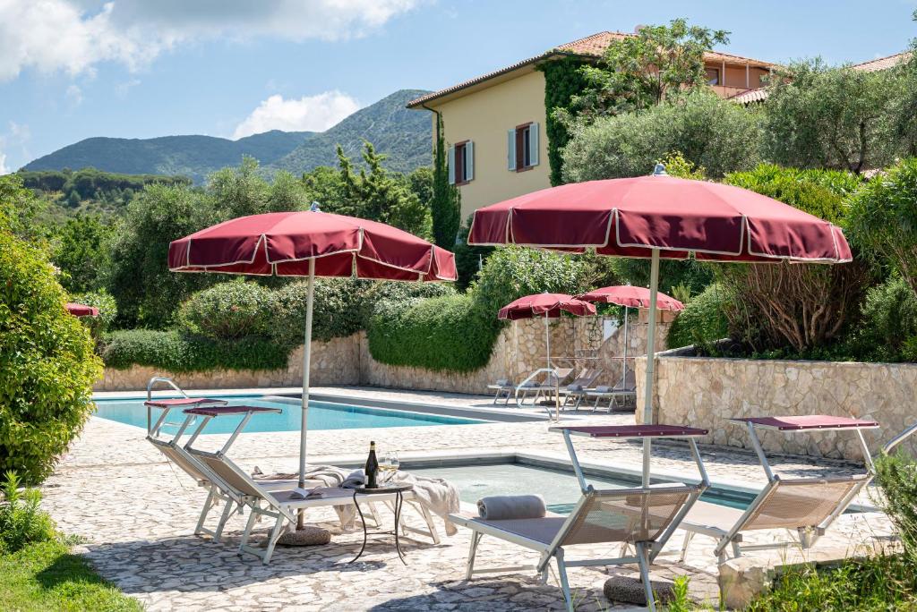 einen Pool mit Stühlen und Sonnenschirmen neben einem Haus in der Unterkunft La Muccheria in San Vincenzo