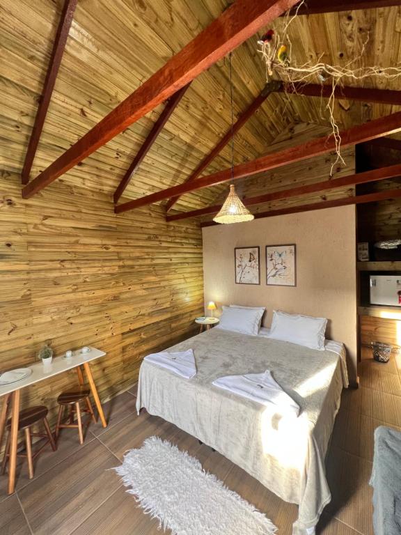 1 dormitorio con 1 cama y pared de madera en Recanto dos Pássaros, en Caparaó Velho