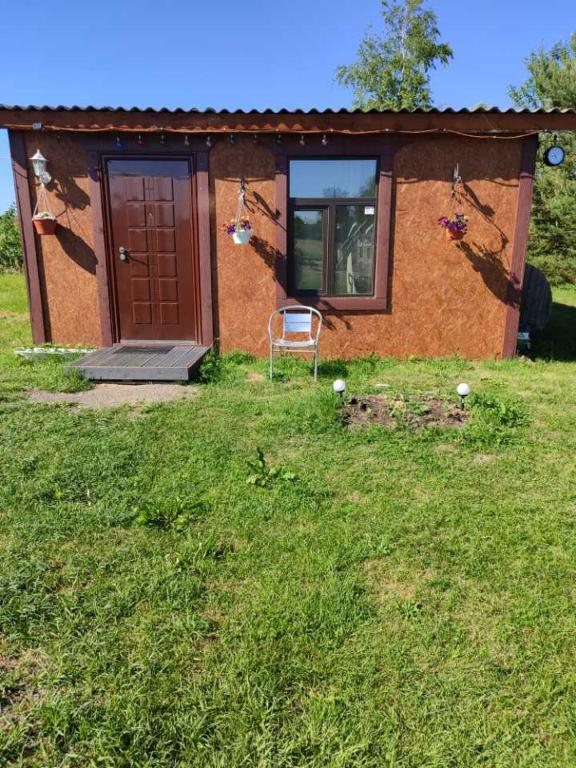 a house with a door and a chair in the grass at Pie Ventas in Ventspils