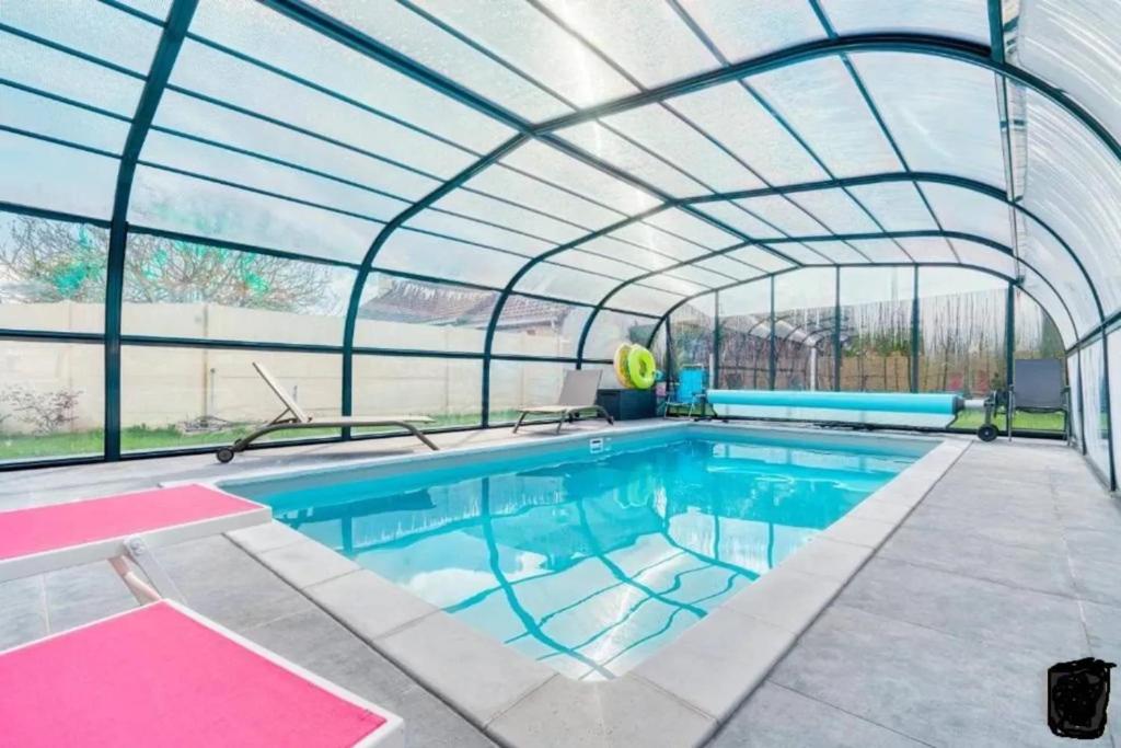une piscine intérieure avec un plafond en verre dans l'établissement Villa confortable à Ranville, piscine privée, à Ranville