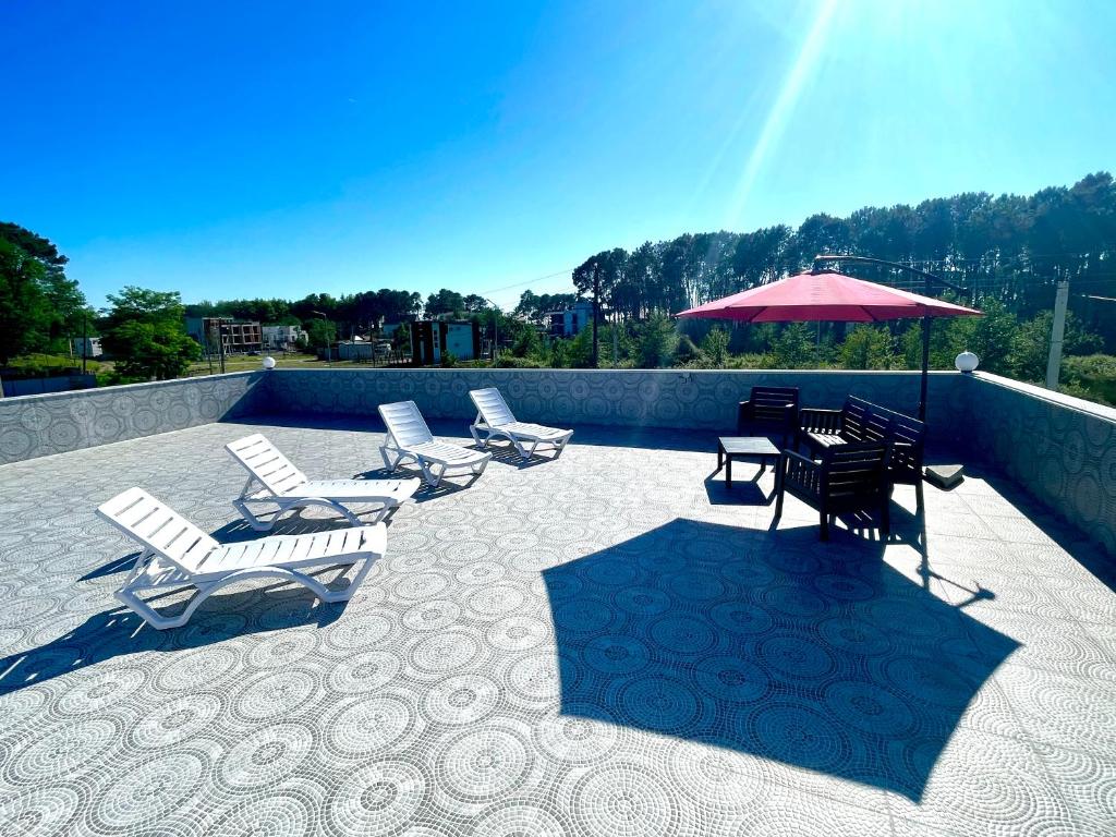 eine Terrasse mit Stühlen, einem Tisch und einem Sonnenschirm in der Unterkunft Villa Capri-Kaprovani in Shekhvetili