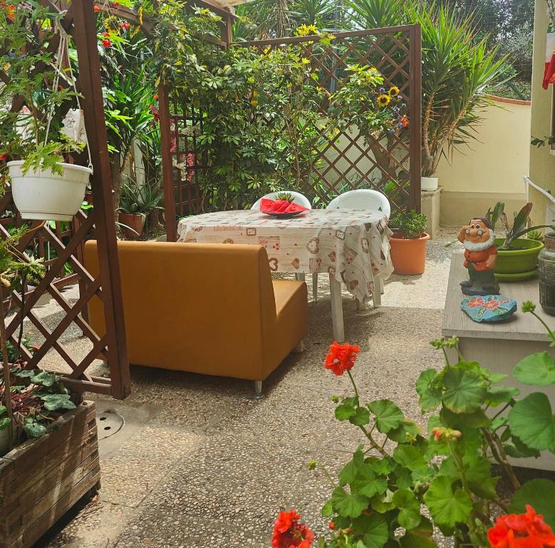 a patio with a couch and a table and flowers at Relax al mare, appartamento Gelsomino in San Vincenzo