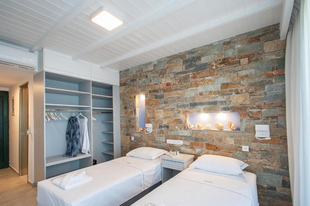 2 Betten in einem Zimmer mit Ziegelwand in der Unterkunft Azzurro in Skiathos-Stadt
