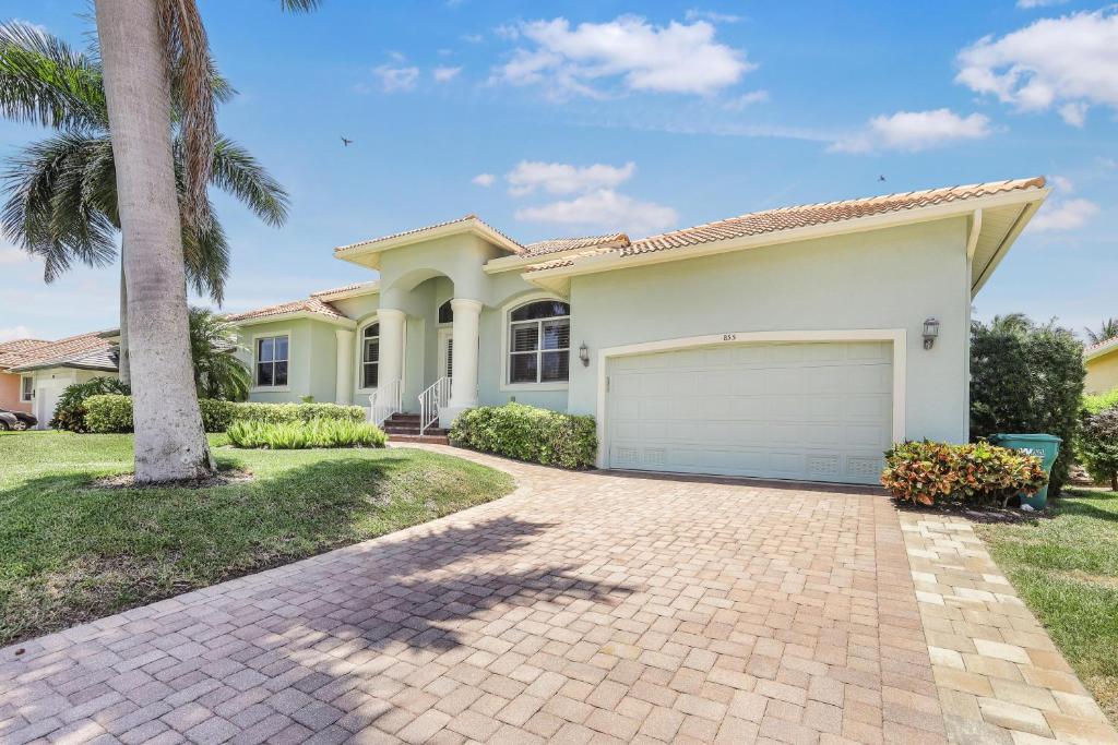 a house with a garage and a palm tree at Pet-friendly waterfront home near beach with pool in Marco Island