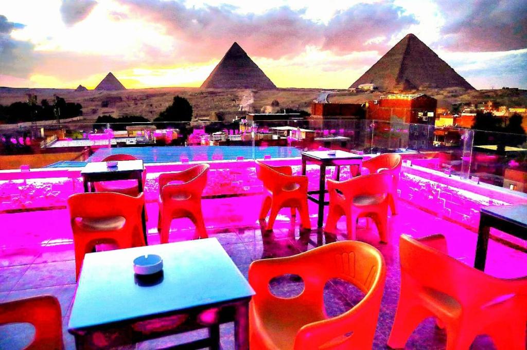 a bar with red chairs and tables and a view of the pyramids at MagiC Pyramids INN in Cairo