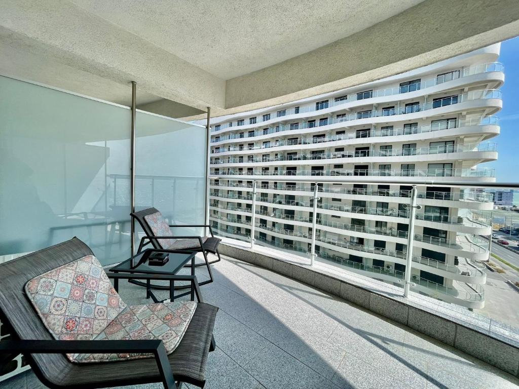 a balcony with two chairs and a large building at Sea and lake view- Casa del Mar in Mamaia Nord