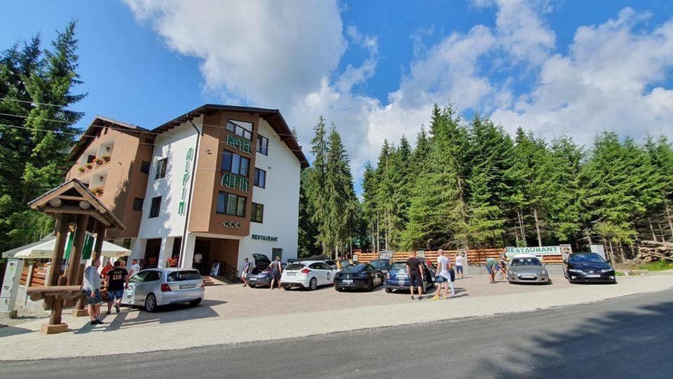 a group of people standing in a parking lot next to a building at Hotel Transalpin in Obarsia-Lotrului