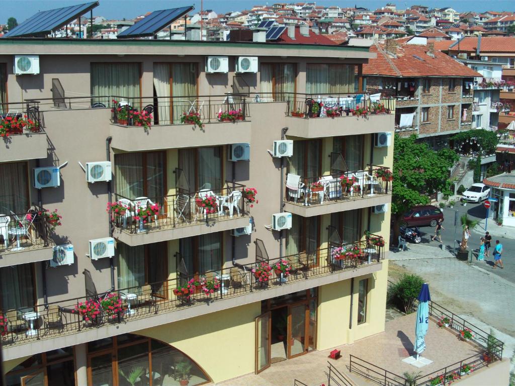 an apartment building with balconies with flowers on it at Kandrovi Sozopol in Sozopol