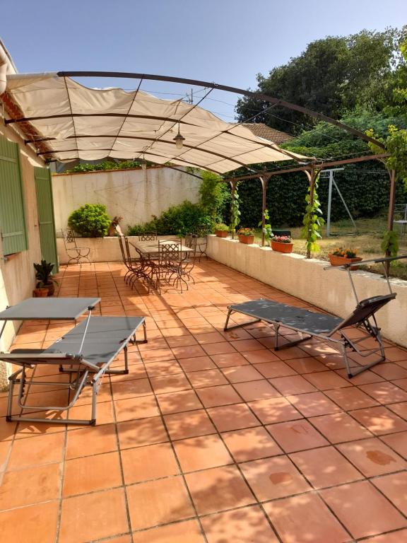 een patio met tafels en stoelen en een parasol bij L'Olivette in Montfrin