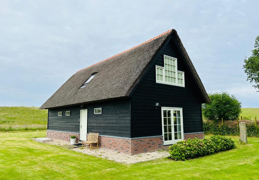 une maison noire avec un toit en gambrel dans l'établissement Villa Nieuwland holiday home, à Den Oever