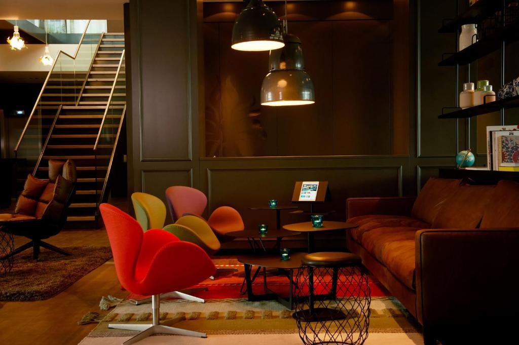 a living room with a couch and a table and chairs at Motel One Amsterdam in Amsterdam