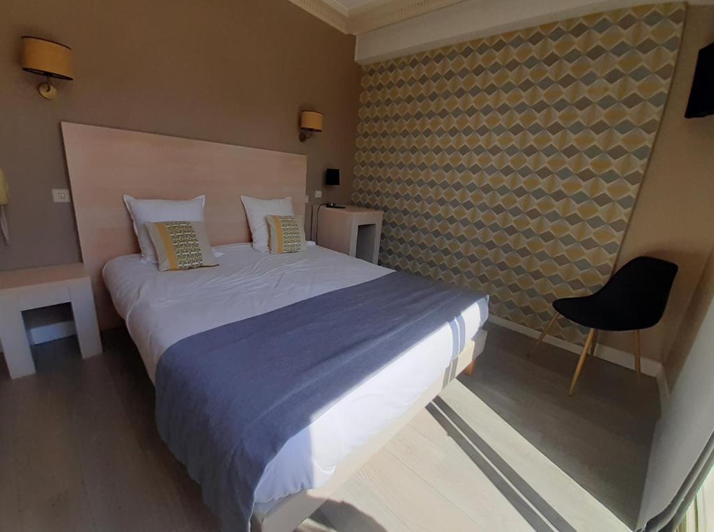 a bedroom with a large bed and a chair at Hôtel Ker-Noyal Quiberon Plage in Quiberon