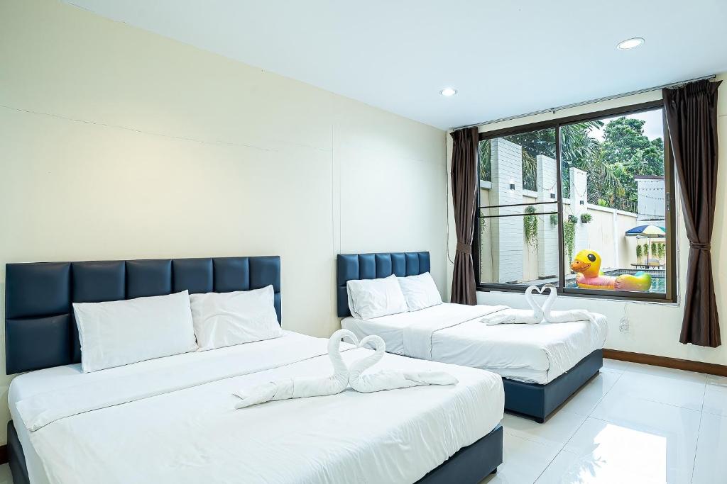 a bedroom with two beds and a window at F&K Pool Villa Pattaya in Jomtien Beach