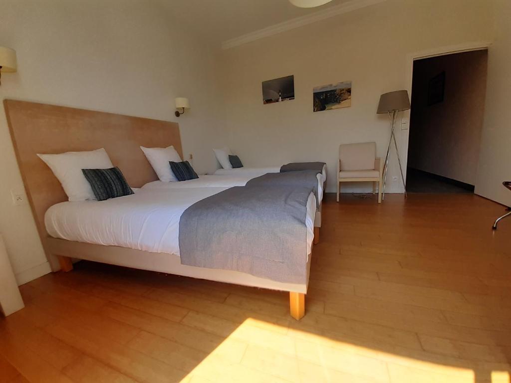 a large white bed in a room with a chair at Hôtel Ker-Noyal Quiberon Plage in Quiberon