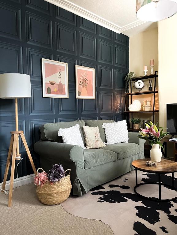 a living room with a green couch in front of a wall at Overleigh Cottage, with optional Hot Tub hire in Chester
